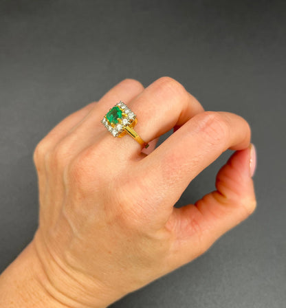 A square shaped emerald and diamond cluster ring in yellow and white gold, modelled on a hand