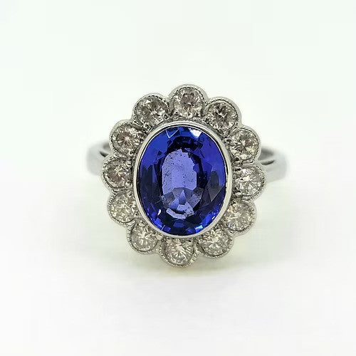 3ct Oval Tanzanite and Diamond Floral Cluster Engagement Ring, 3ct oval-cut tanzanite surrounded by 1ct round brilliant-cut diamonds in classic floral design in 18ct white gold