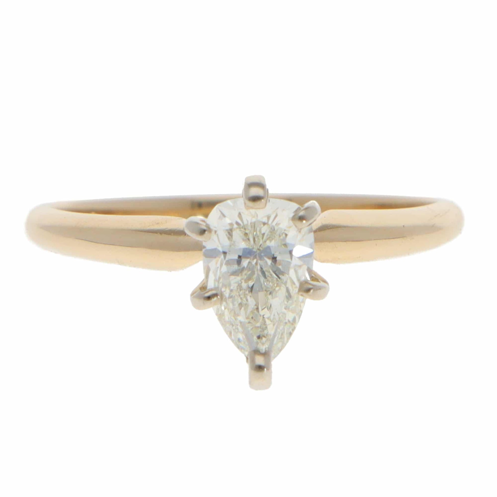 A single stone pear cut diamond ring in yellow and white gold, on a white background