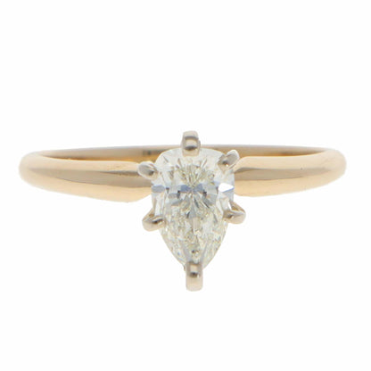 A single stone pear cut diamond ring in yellow and white gold, on a white background