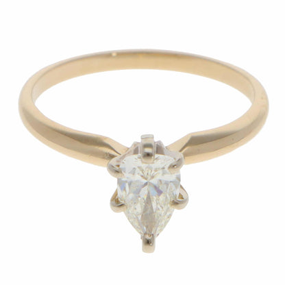A single stone pear cut diamond ring in yellow and white gold, on a white background