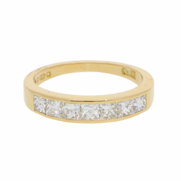 A yellow gold half eternity band ring with princess cut diamonds, on a white background