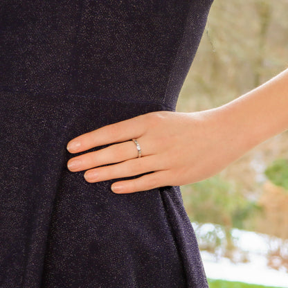 A white gold brilliant cut diamond eternity band, modelled by a woman wearing a black dress
