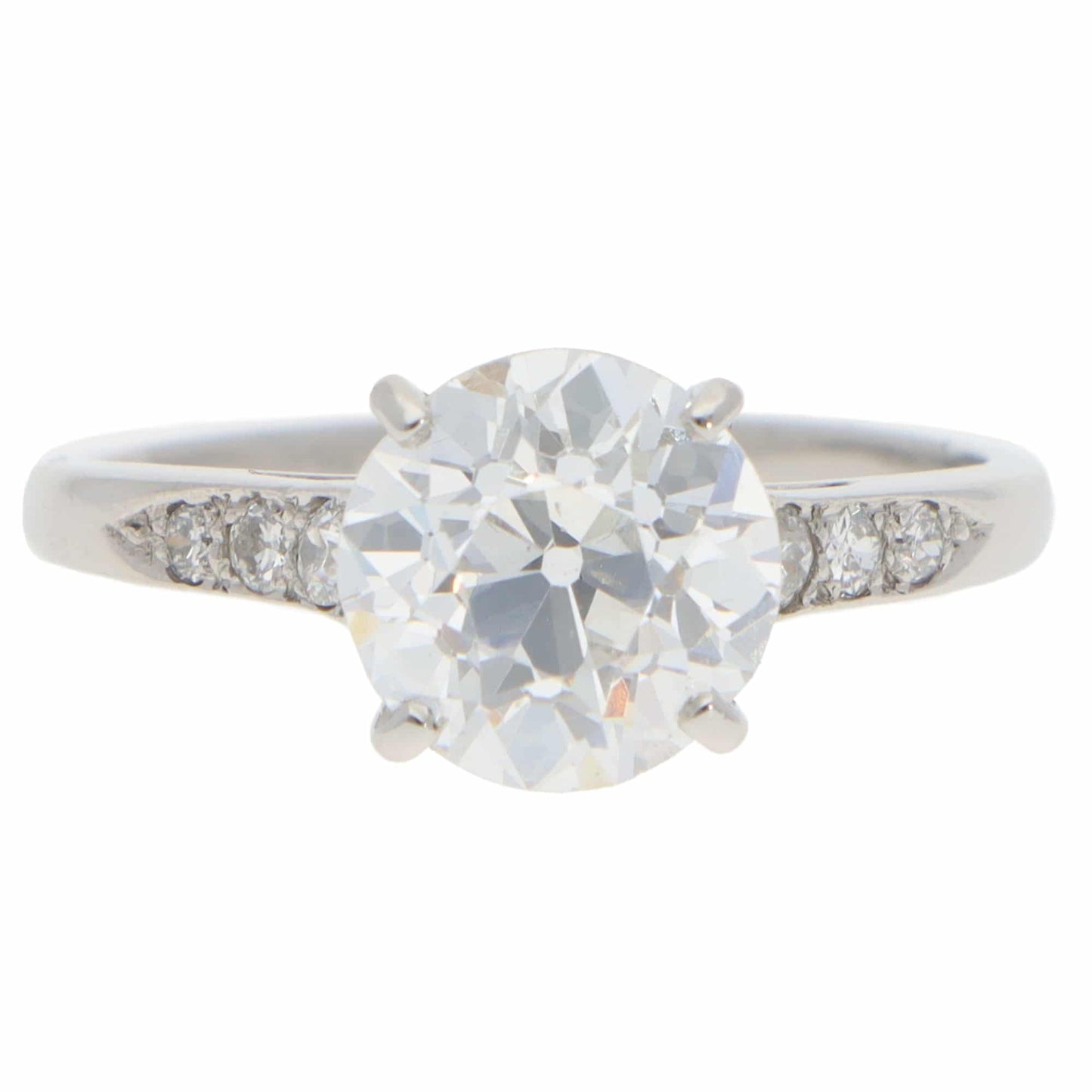 A round old cut diamond ring with diamond shoulders in platinum, on a white background
