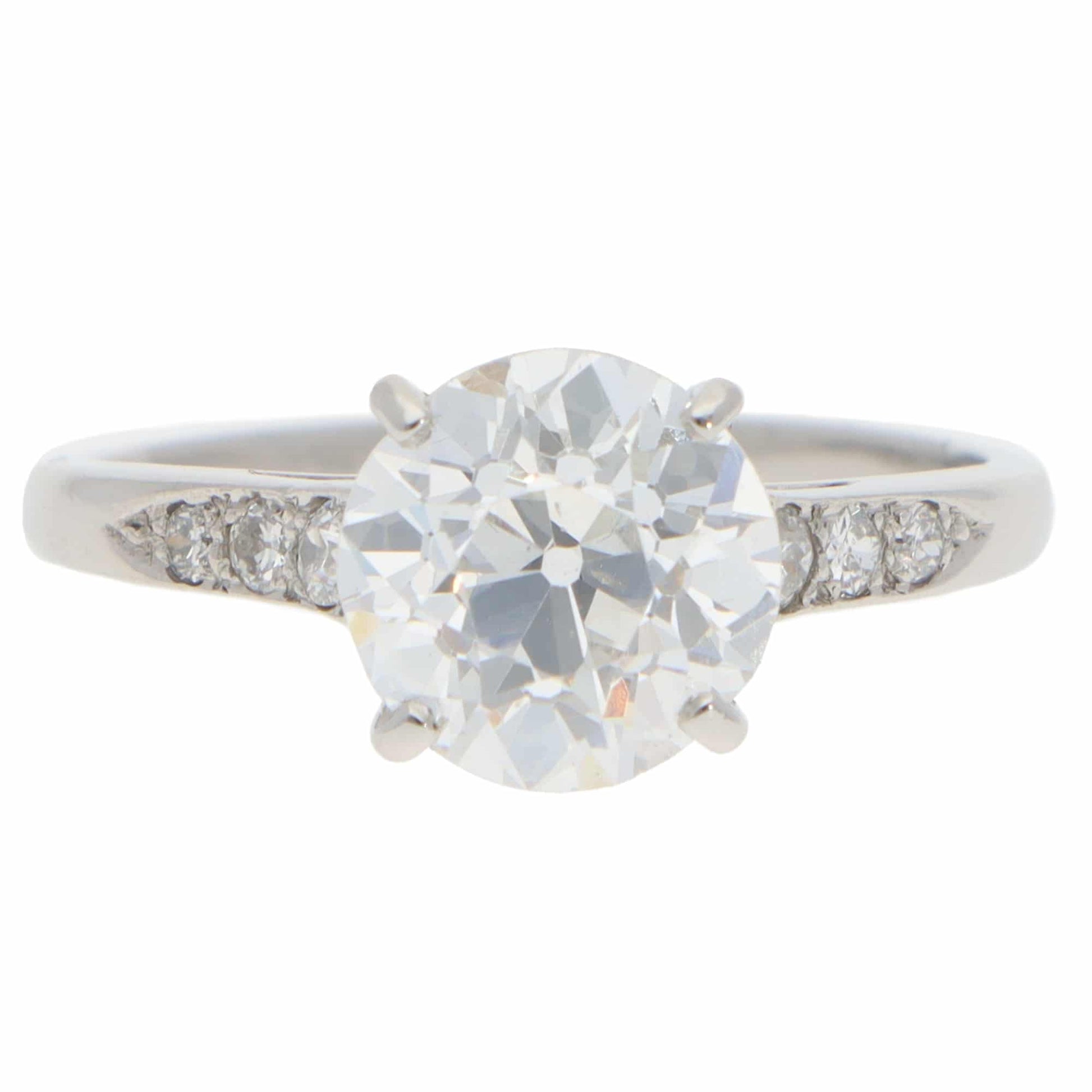 A round old cut diamond ring with diamond shoulders in platinum, on a white background