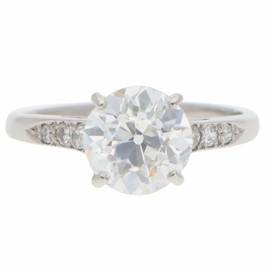 A round old cut diamond ring with diamond shoulders in platinum, on a white background