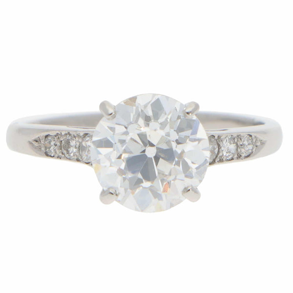 A round old cut diamond ring with diamond shoulders in platinum, on a white background