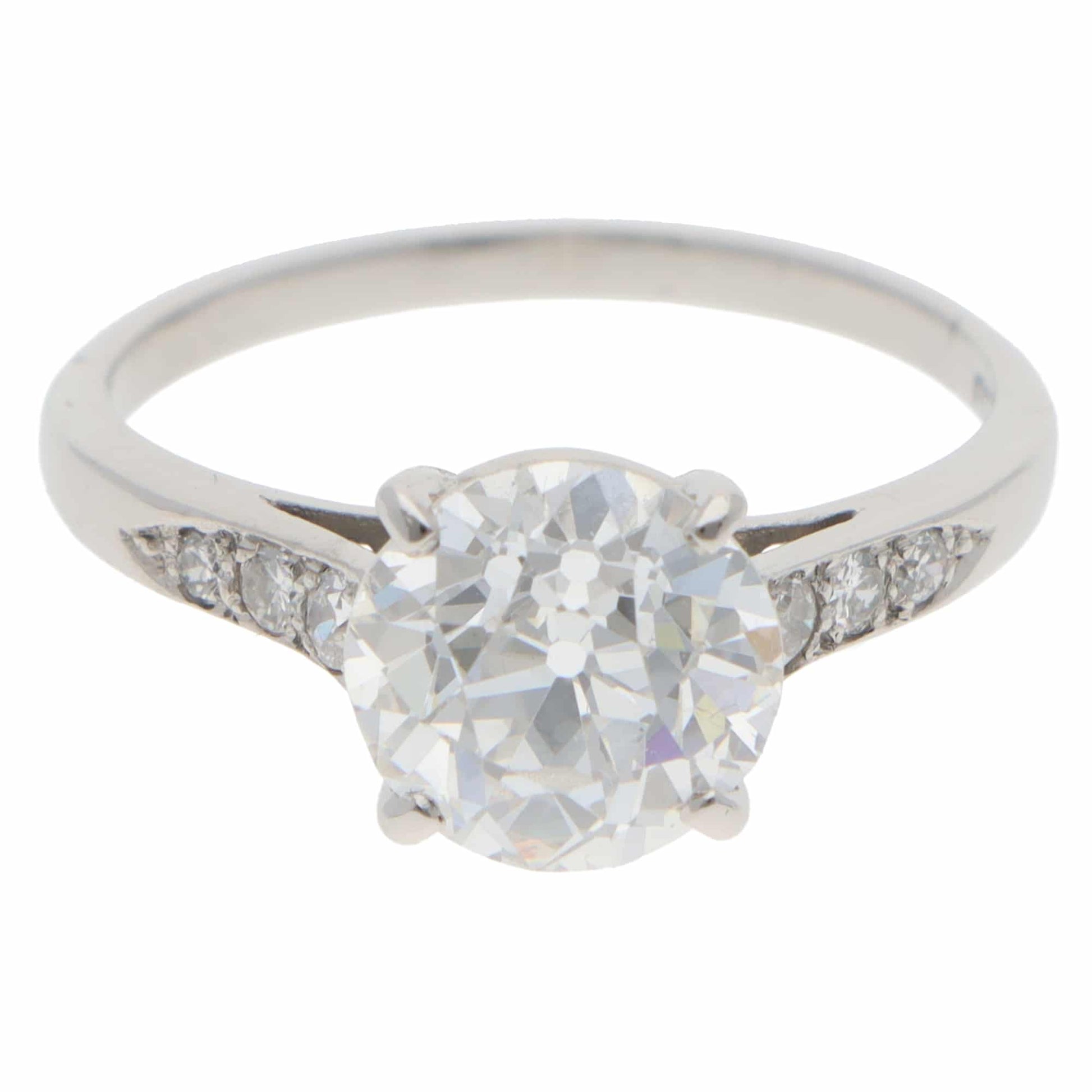 A round old cut diamond ring with diamond shoulders in platinum, on a white background