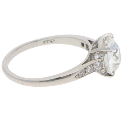 A round old cut diamond ring with diamond shoulders in platinum, stamped PLAT, on a white background