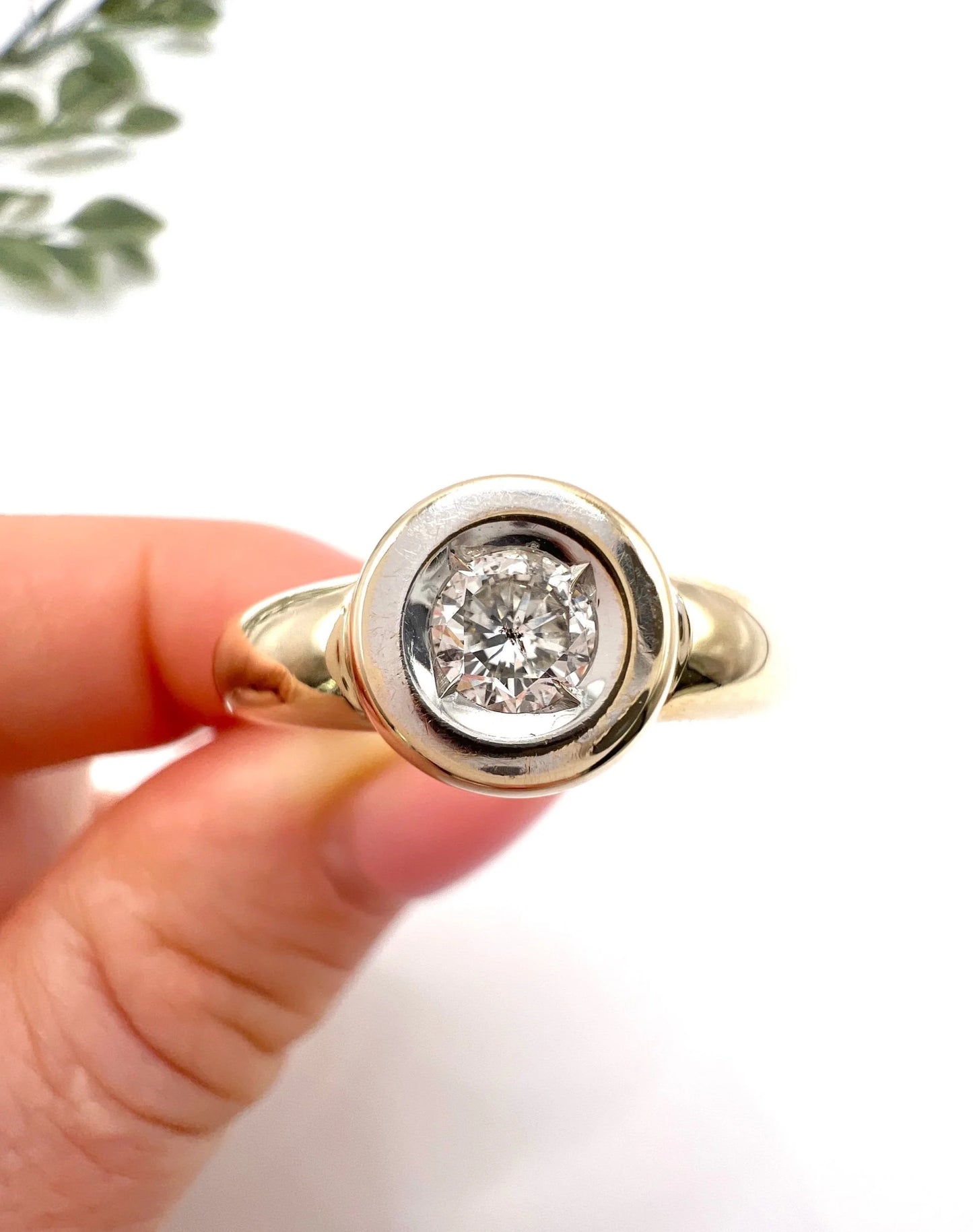 A single stone brilliant cut diamond ring bezel set in yellow gold, held in a hand