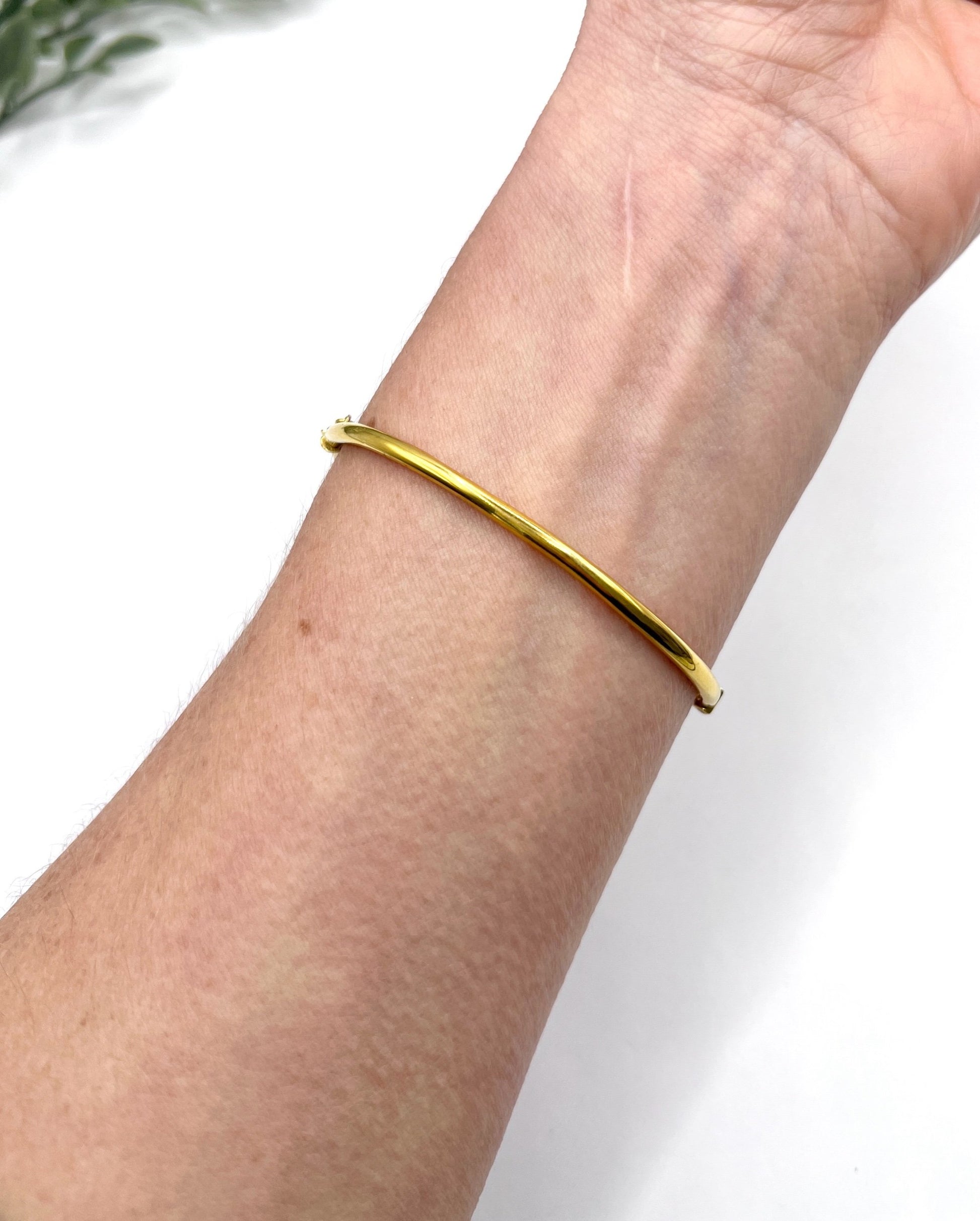 A yellow gold bangle bracelet set with rubies and seed pearls, modelled on a wrist