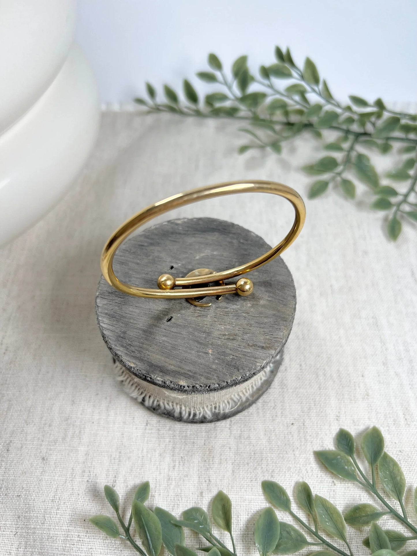 A yellow gold crossover bangle bracelet with a pearl and turquoise crescent moon centre