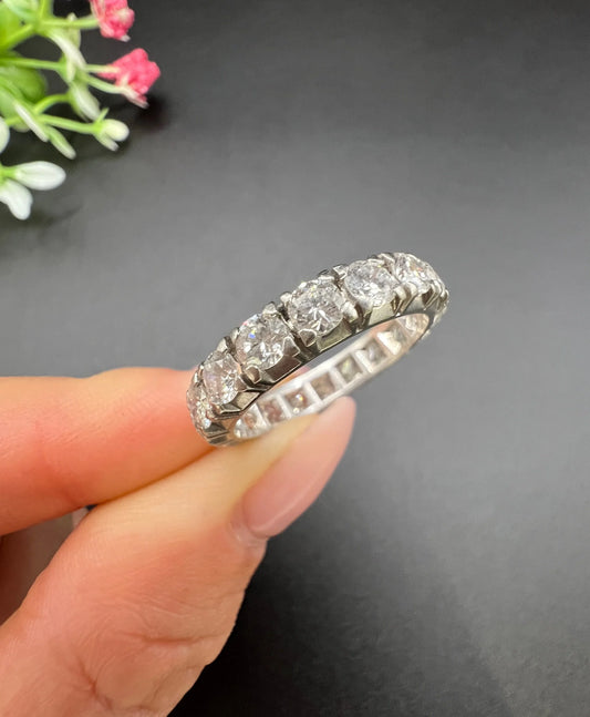 A white metal diamond full eternity band ring, held in a hand