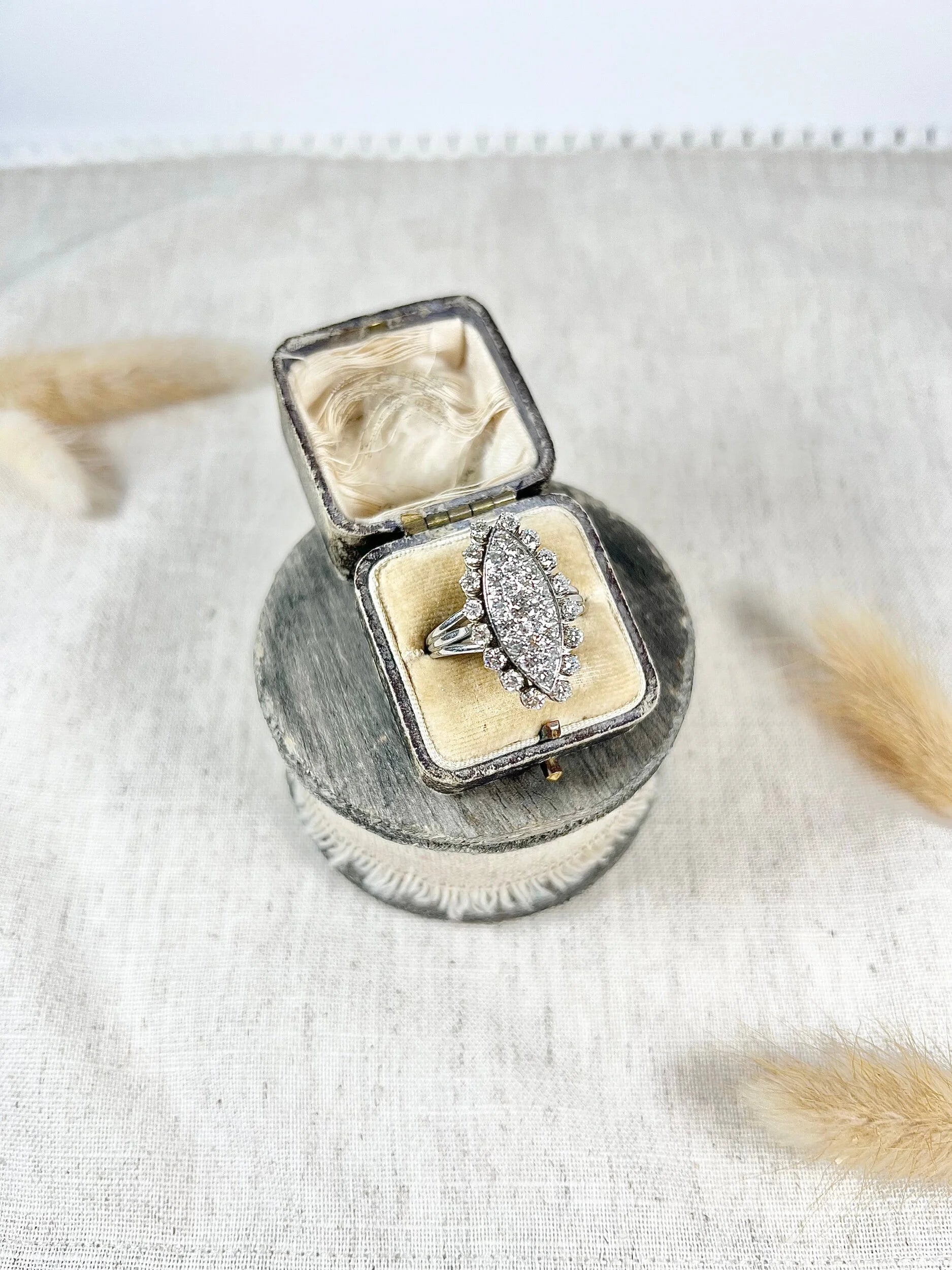 A navette shaped diamond cluster ring in white metal, in an antique ring box