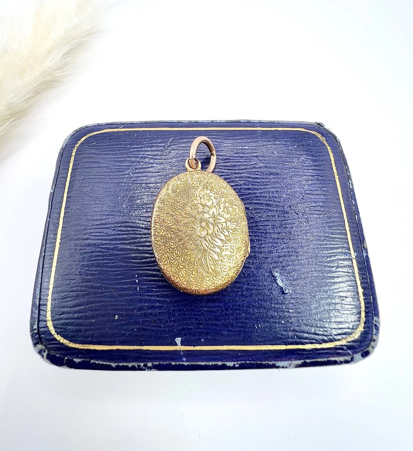 An oval yellow gold locket with floral engraving