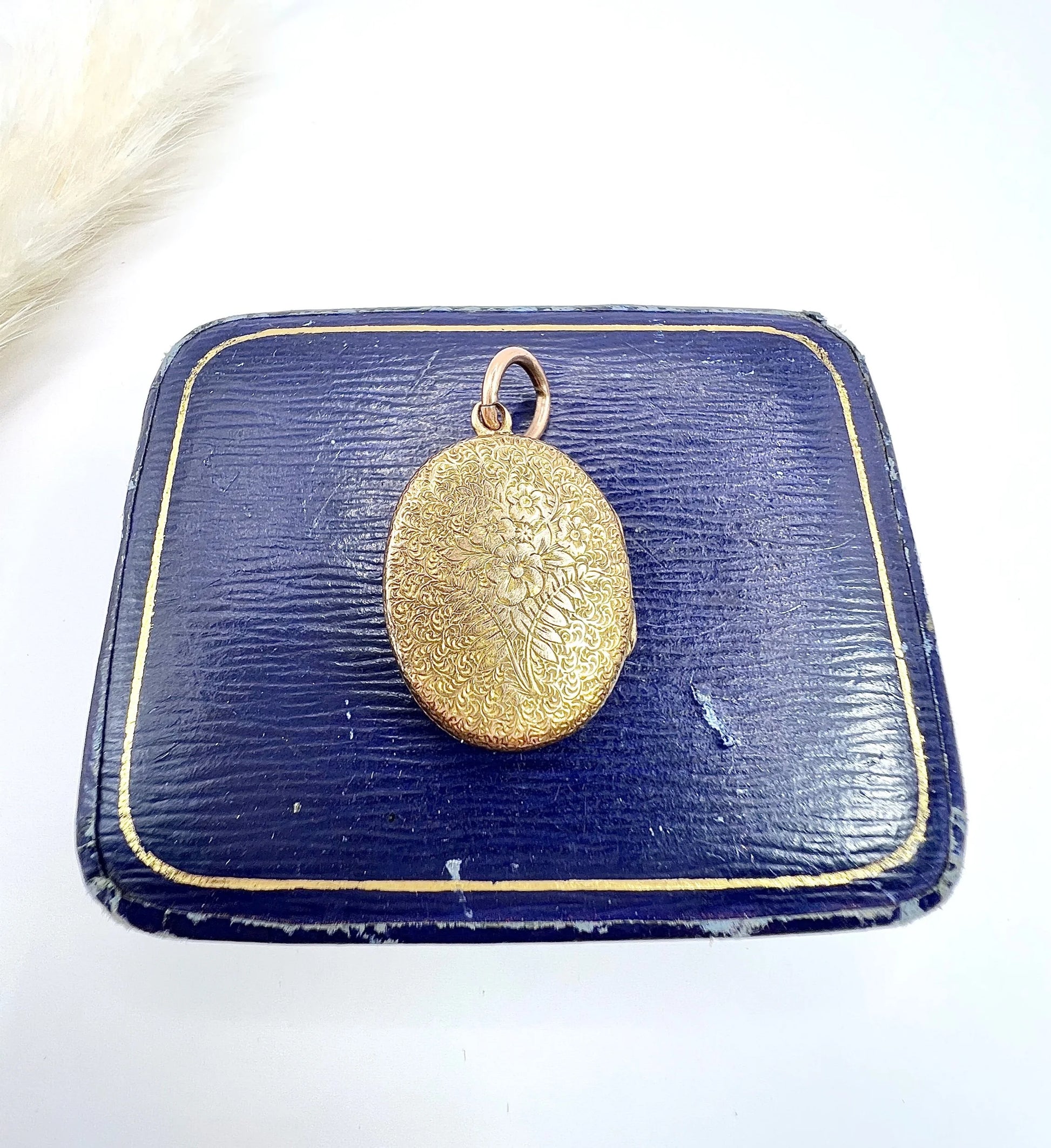 An oval yellow gold locket with floral engraving