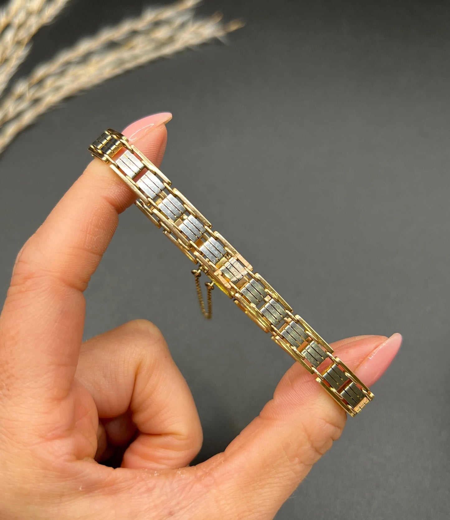 A gold and platinum gate bracelet, held in a hand