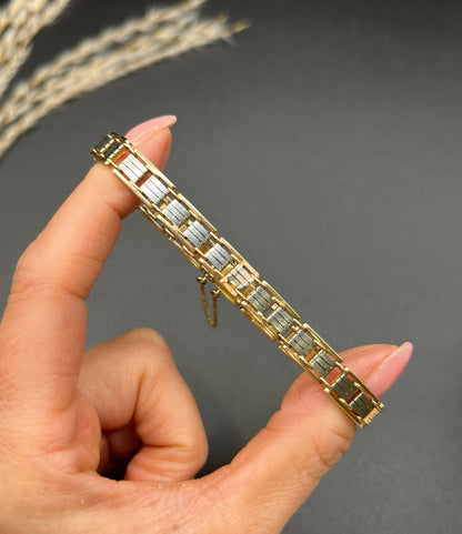 A gold and platinum gate bracelet, held in a hand