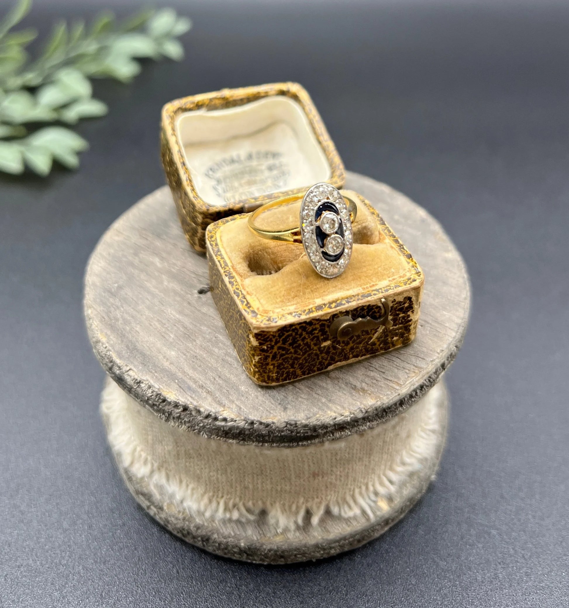 An oval cluster ring with diamonds and sapphires in platinum and yellow gold, in an antique ring box