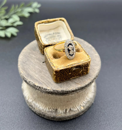 An oval cluster ring with diamonds and sapphires in platinum and yellow gold, in an antique ring box