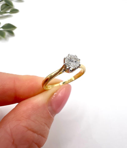 A single stone brilliant cut diamond ring claw set in platinum and yellow gold, held in a hand