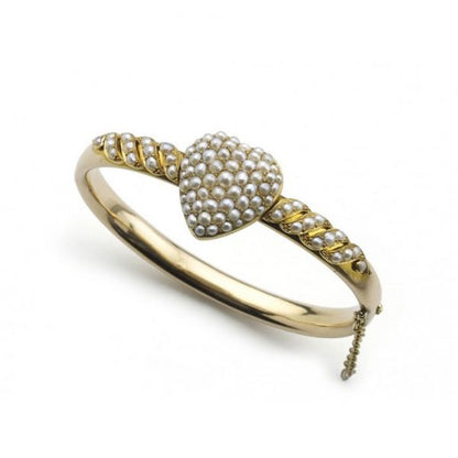 Antique Victorian Pearl Bangle Bracelet; hinged bangle set with seed pearl heart to the centre and seed pearls set in a scroll design to each side, with a glass locket compartment to the reverse of the heart, in 14ct yellow gold, Circa 1880