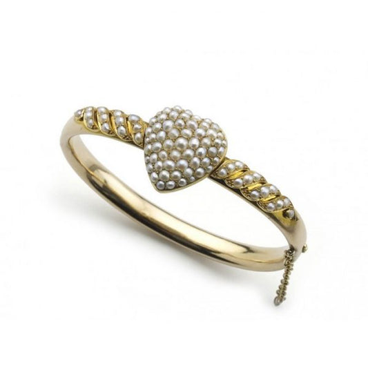 Antique Victorian Pearl Bangle Bracelet; hinged bangle set with seed pearl heart to the centre and seed pearls set in a scroll design to each side, with a glass locket compartment to the reverse of the heart, in 14ct yellow gold, Circa 1880