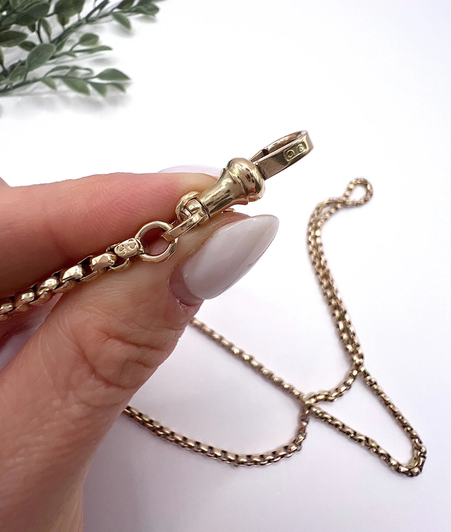 A long rose gold link necklace with swivel clasp, held in a hand