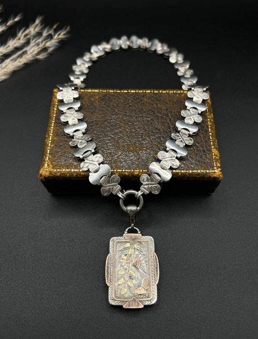 An antique rectangular locket with gold inlay, on a book collar necklace