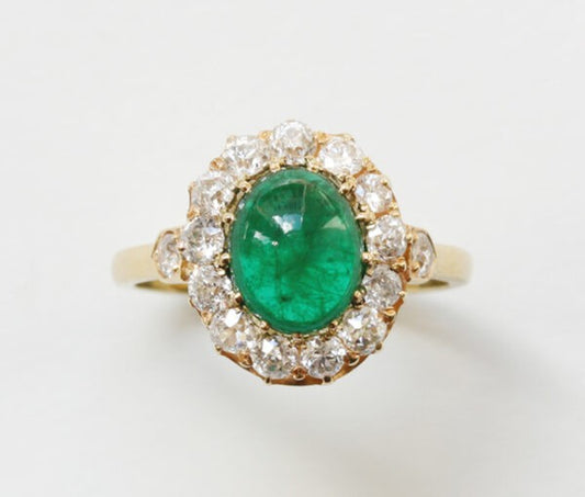 Antique Edwardian Oval Cabochon Emerald and Diamond Cluster Ring; 2.70ct oval cabochon cut emerald surrounded by 1.65cts old-cut diamonds, 18ct yellow gold