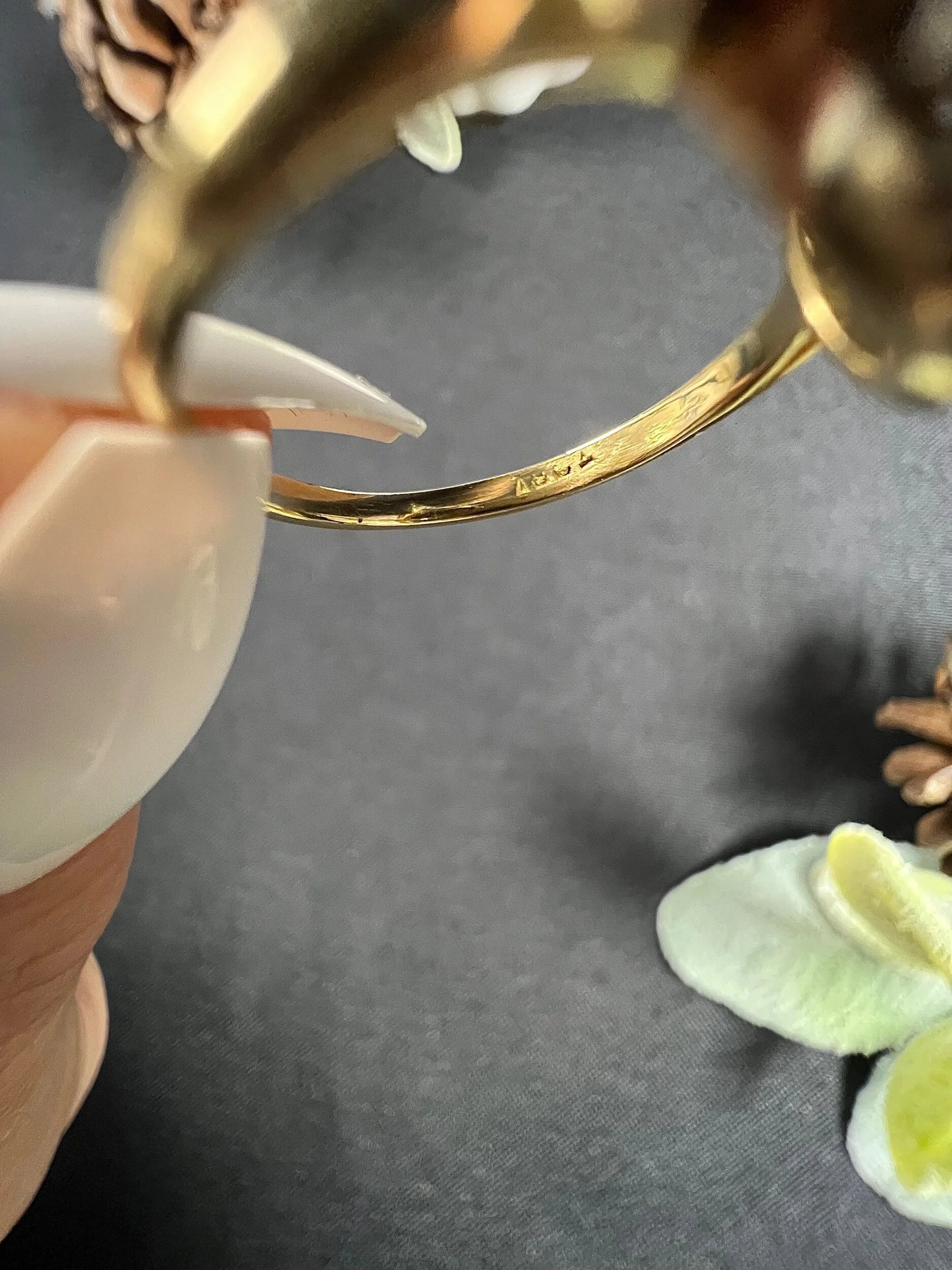 A close-up of a stamp inside a gold ring shank, held in a hand