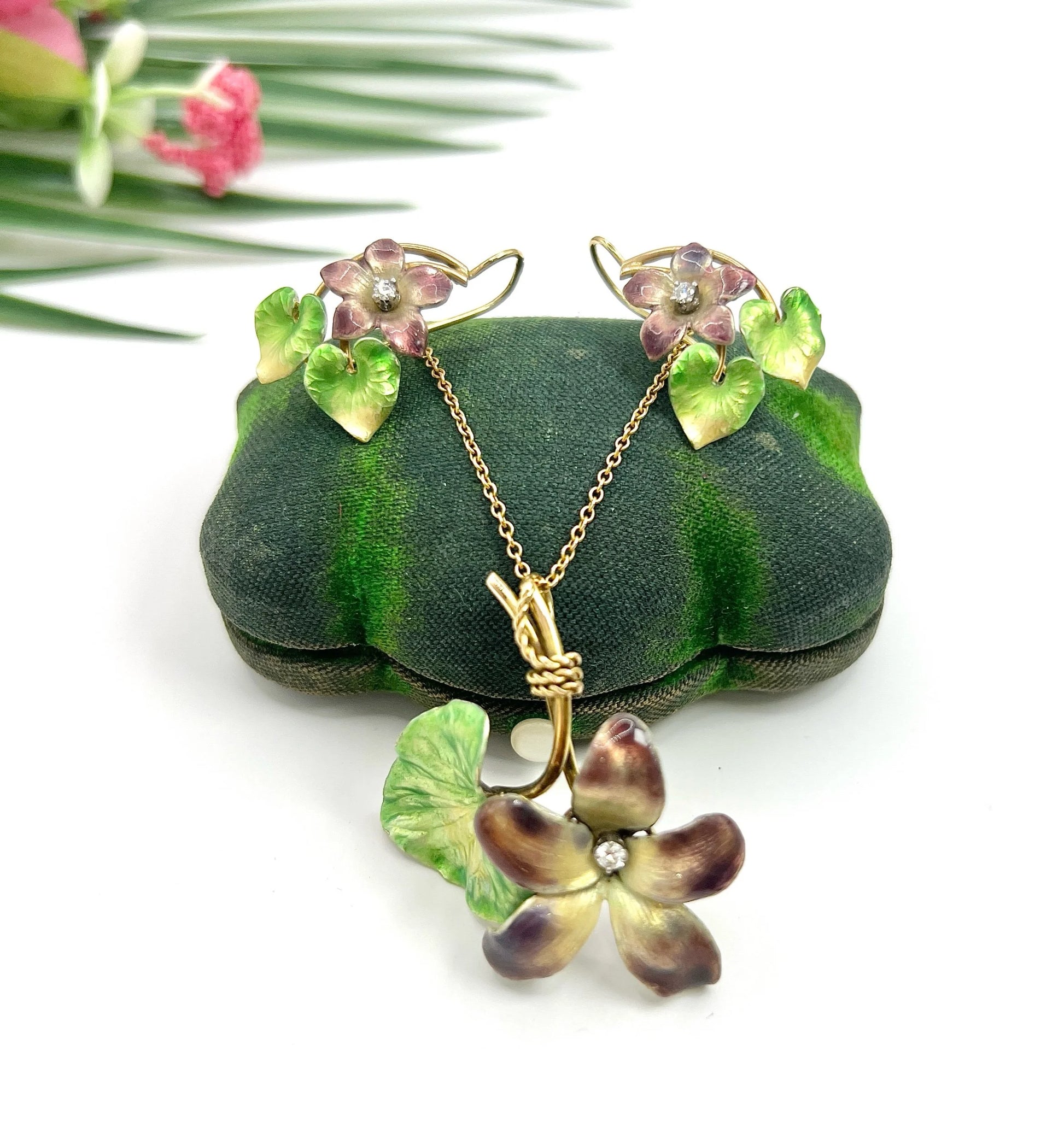 Gold and enamel diamond flower pendant and earrings, with a gold chain, on a green vintage jewellery box