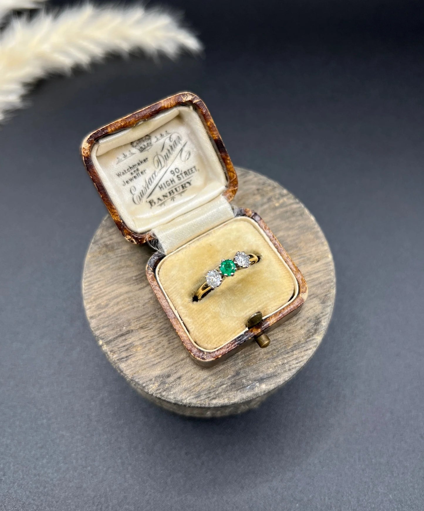 A three stone emerald and diamond ring in yellow gold and platinum, in an antique ring box