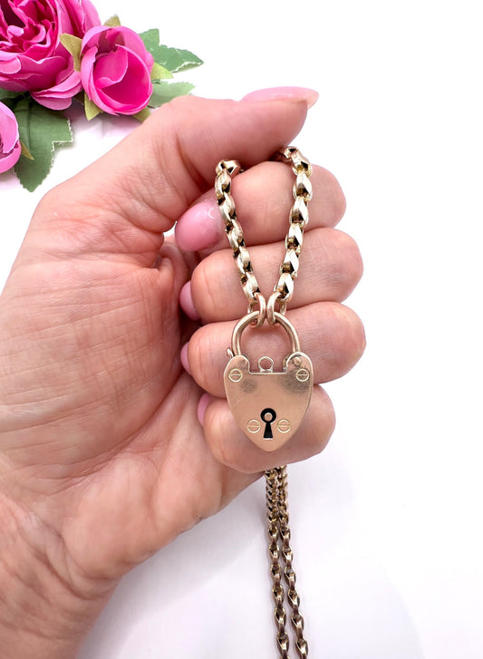 A rose gold heart padlock on a rose gold chain, held in a hand