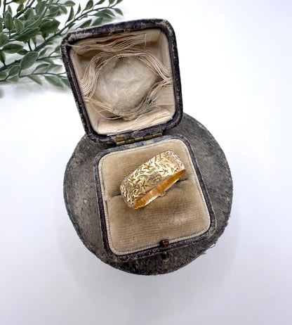 A yellow gold ornate engraved buckle band ring, in an antique ring box