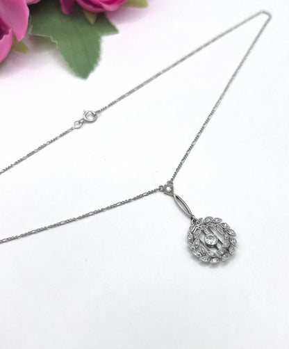 A platinum floral wreath pendant with diamonds on a platinum chain