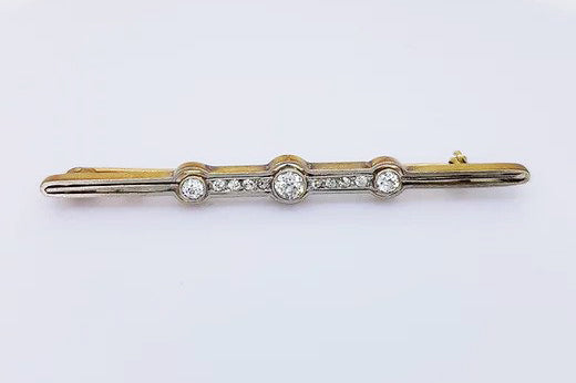 Antique Diamond Bar Brooch; consisting of three diamonds connected via diamond set links. Set in platinum and mounted on 15ct yellow gold.