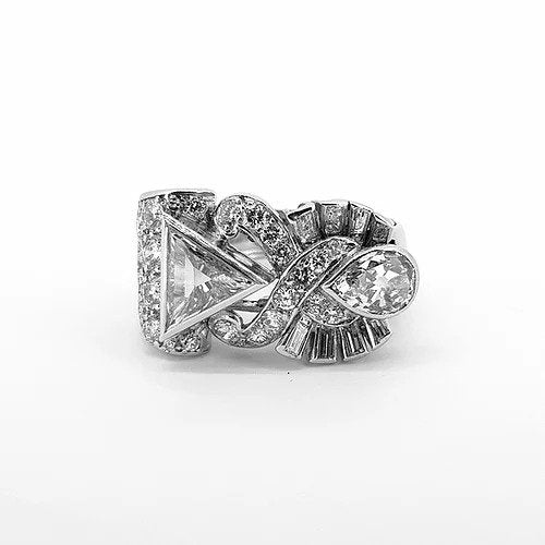 Vintage Trilliant, Pear and Baguette Cut Diamond Abstract Crossover Dress Ring; bezel set triangular diamond surrounded by an openwork cross over detail of pave set diamonds, reaching to the tip of a bezel set pear shaped diamond with a fan of baguette diamonds to each side