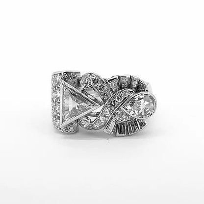 Vintage Trilliant, Pear and Baguette Cut Diamond Abstract Crossover Dress Ring; bezel set triangular diamond surrounded by an openwork cross over detail of pave set diamonds, reaching to the tip of a bezel set pear shaped diamond with a fan of baguette diamonds to each side