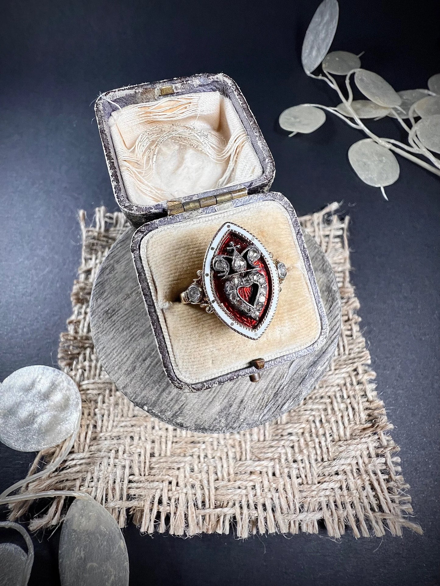 An ornate diamond and enamel navette shaped antique ring, in an antique ring box