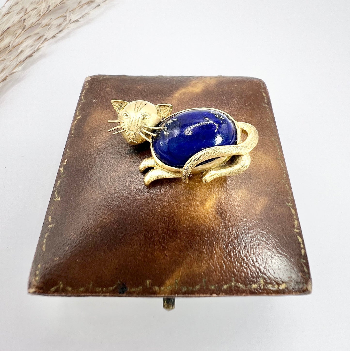 A yellow gold cat brooch with a lapis lazuli body
