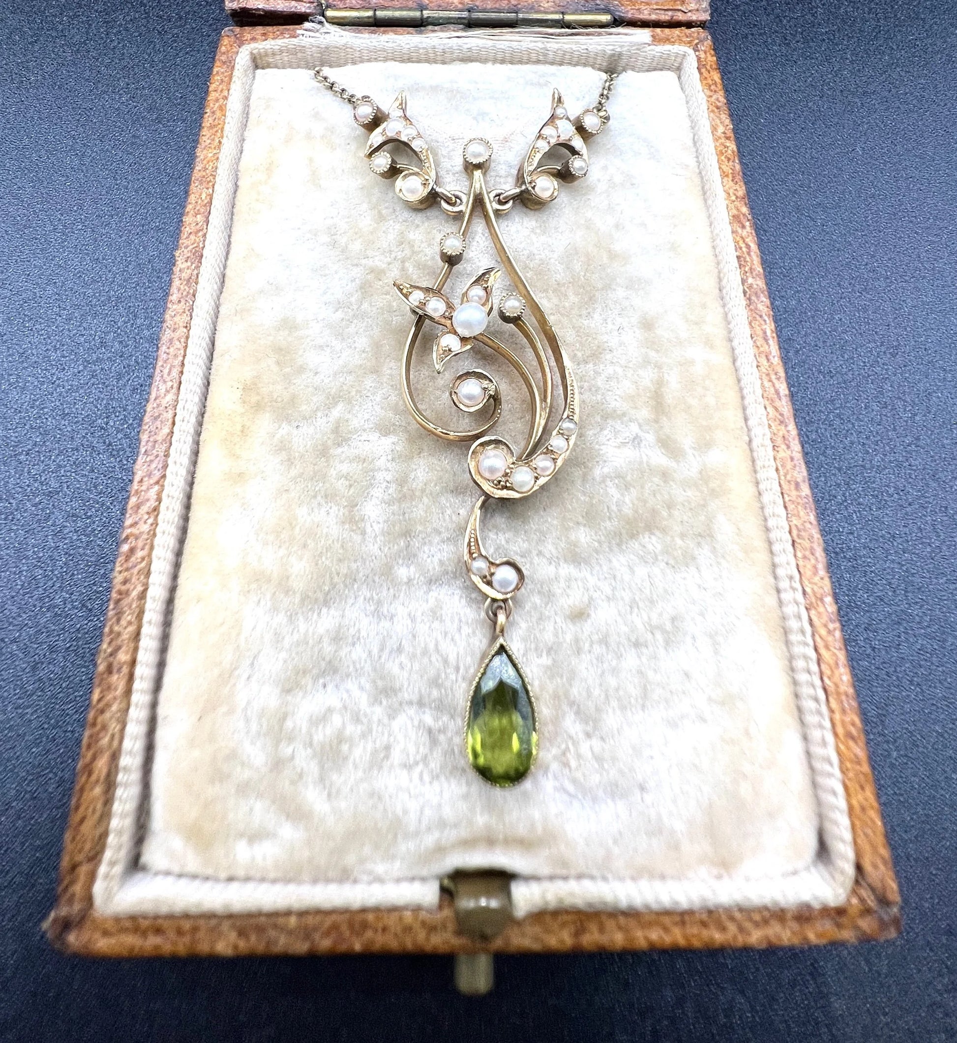A yellow gold floral pendant necklace with pearls and a peridot drop, in an antique box
