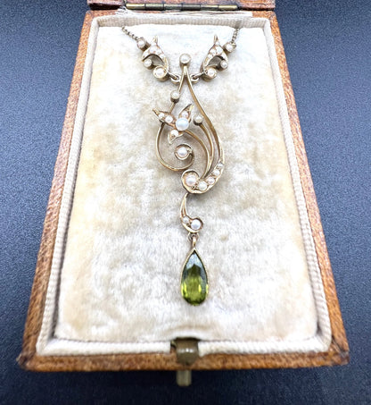 A yellow gold floral pendant necklace with pearls and a peridot drop, in an antique box