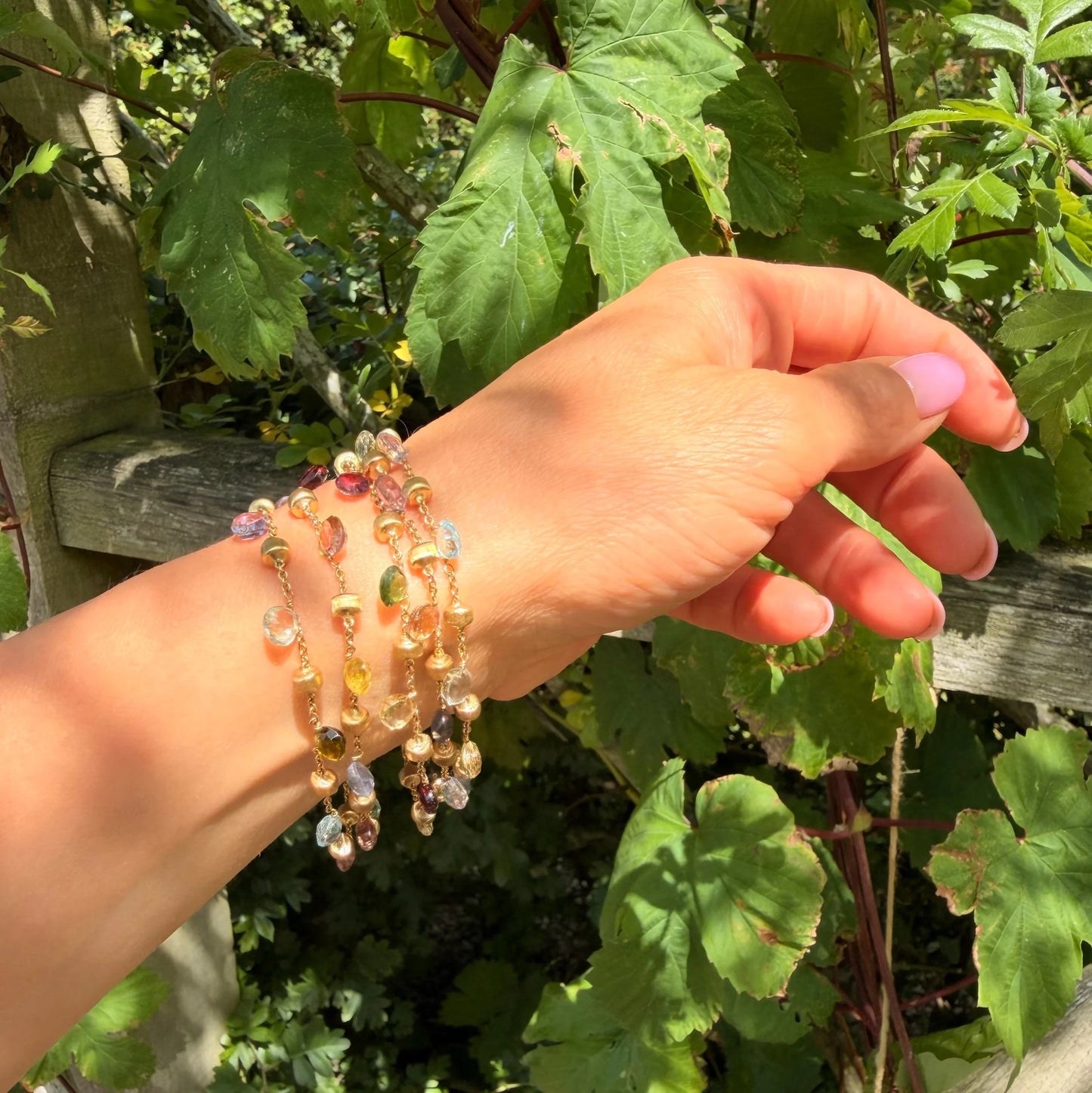 A yellow gold five row multi-gemstone bracelet, modelled on a wrist