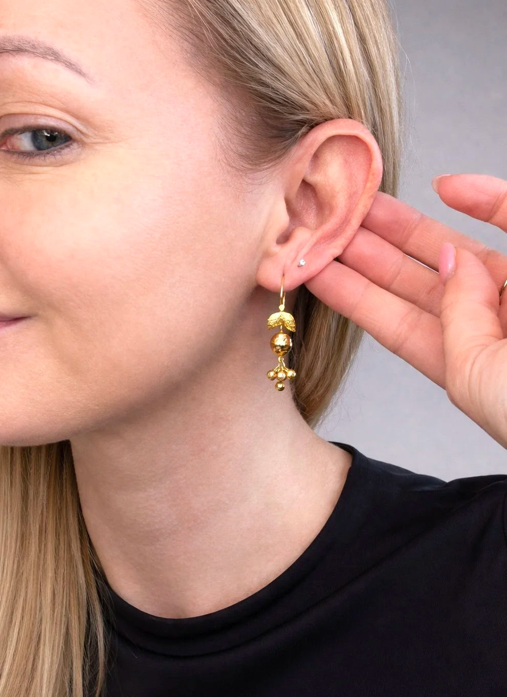 A yellow gold leaf and faceted ball drop earring, modelled in an ear