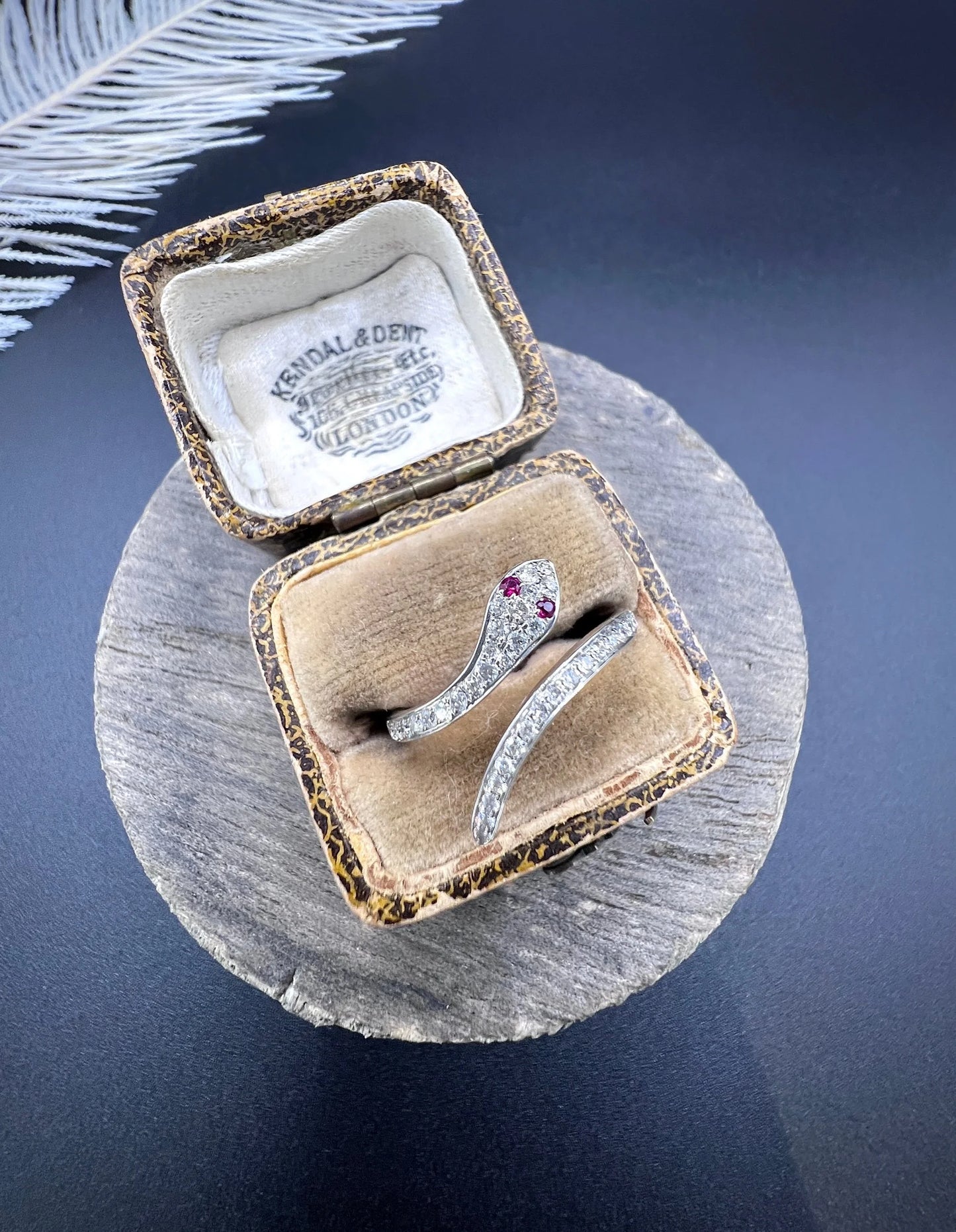 A white gold snake ring set with diamonds and with ruby eyes, in an antique ring box