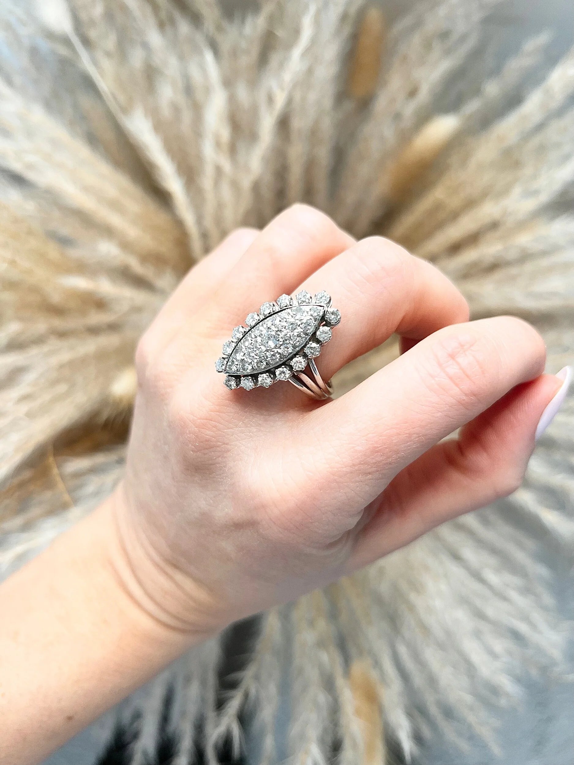 A navette shaped diamond cluster ring in white metal, modelled on a hand