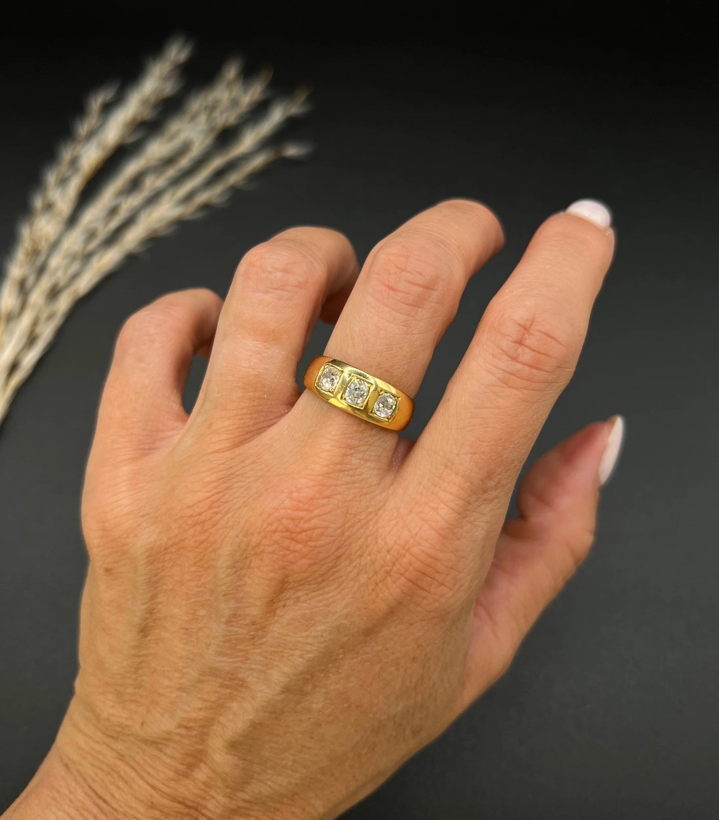A three stone old cut diamond ring in yellow gold, modelled on a hand