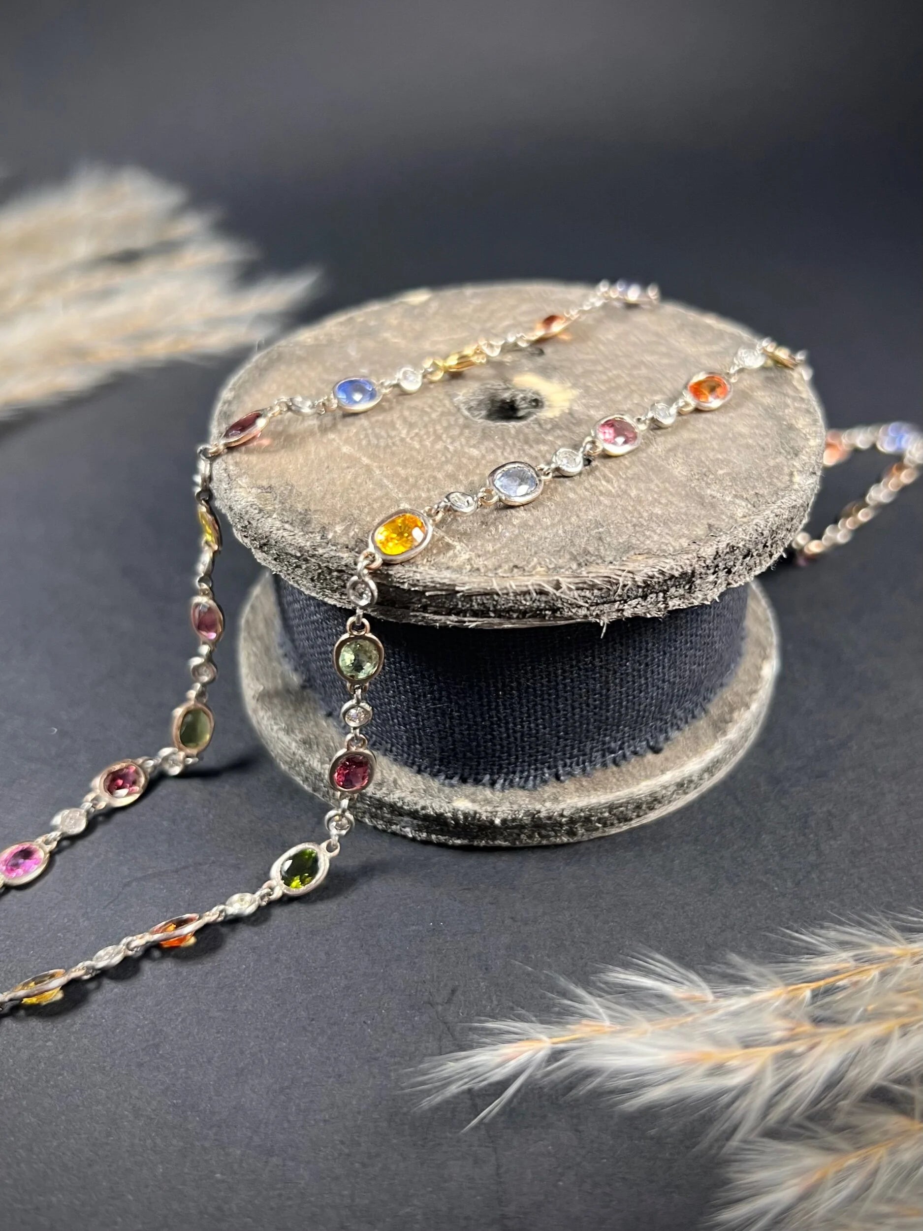 A coloured sapphire and diamond set necklace in platinum and gold, on a wooden object