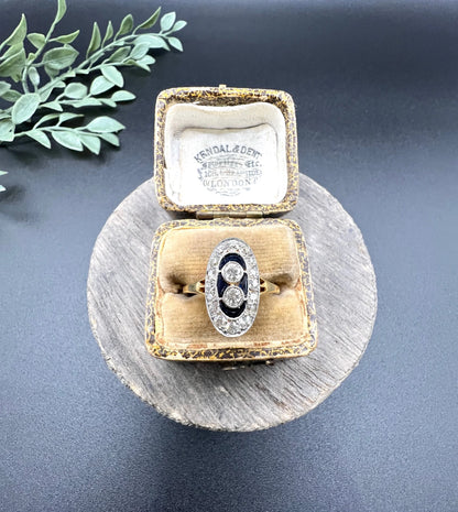 An oval cluster ring with diamonds and sapphires in platinum and yellow gold, in an antique ring box